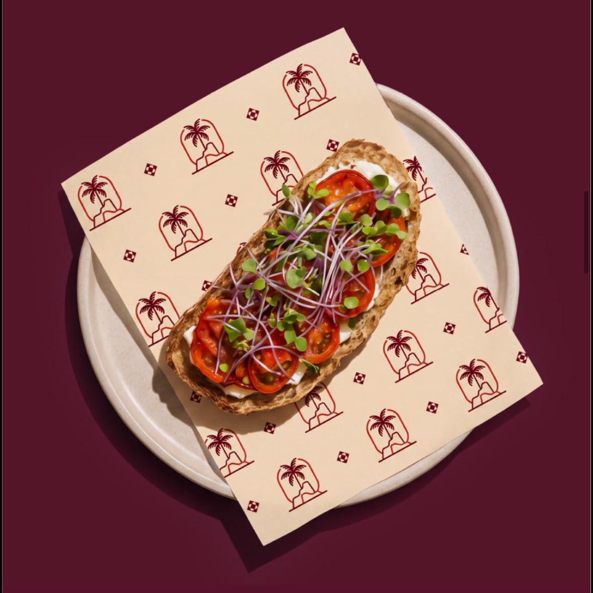 Open toast topped with roasted tomatoes and microgreens, served on Ain Al Shay branded paper